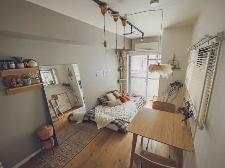 ナチュラルカラーのワンルーム、寝室とダイニングが配置された雰囲気のある空間