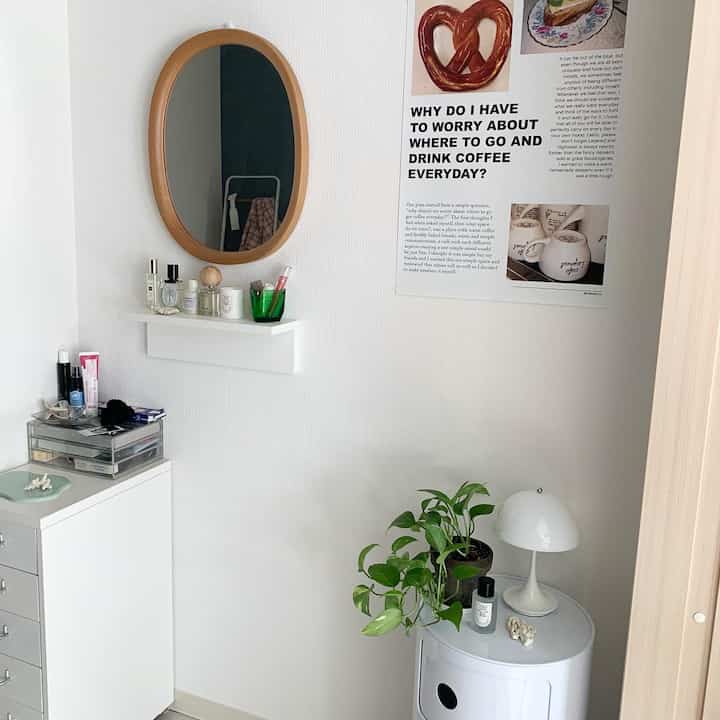Compact and clean white space featuring wood-tone mirror and vanity with green plants