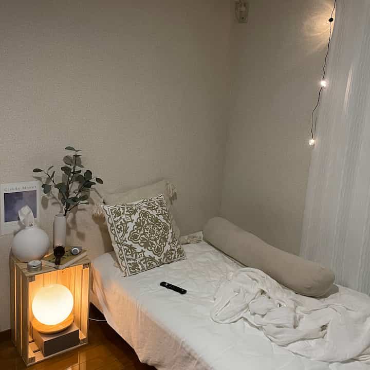 落ち着いたベージュ調の寝室、ベッドとナチュラルな小物が配置された居心地の良い空間