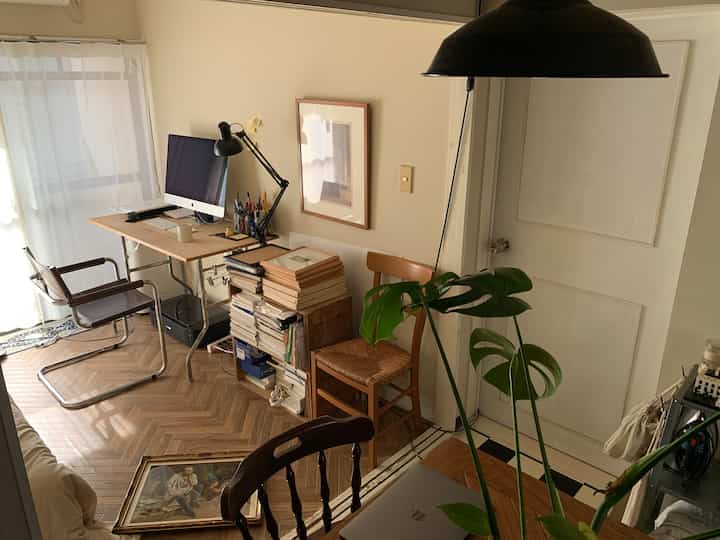 ナチュラルな色調のホームオフィス、ヴィンテージの額縁と木目調の家具が配置された雰囲気のある作業空間