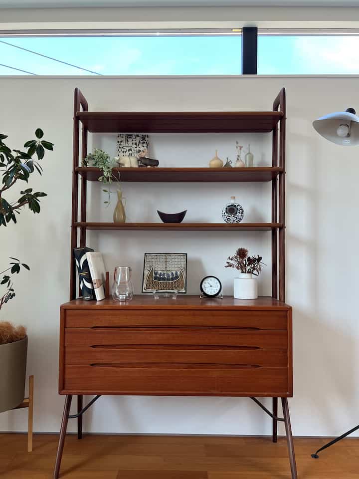 ナチュラルな色調のリビング家具、木製のキャビネットと棚に植物やオブジェが配置された落ち着いた空間