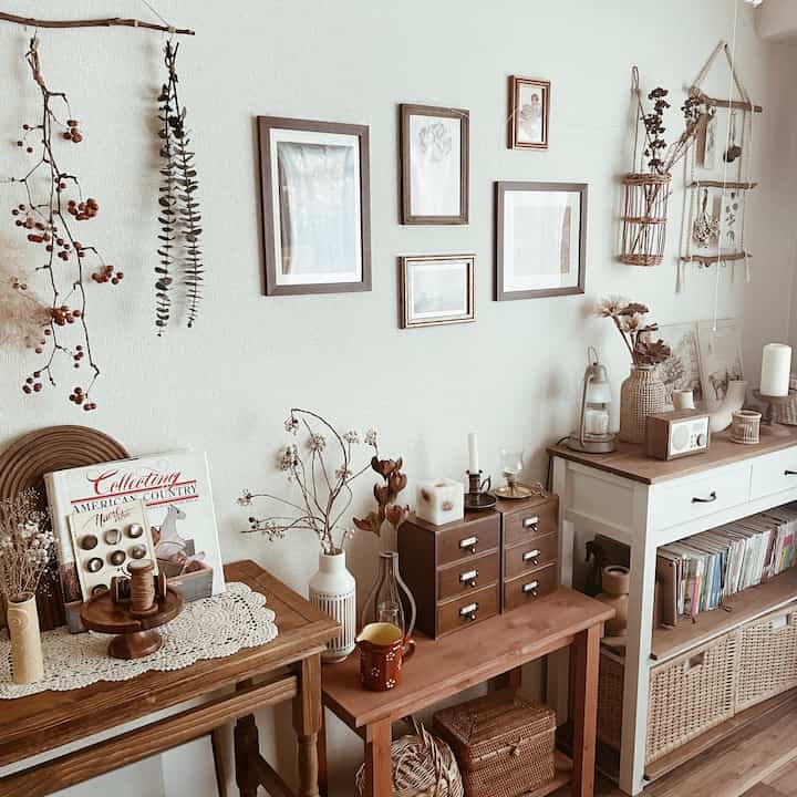 ベージュとブラウンのナチュラルトーンのリビング、収納家具とヴィンテージ風の額装が配置された温かみのあるインテリア