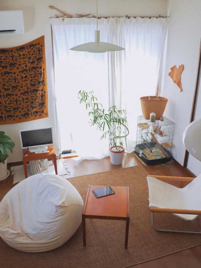 ライトブラウンとホワイトの色調のリビング、コーヒーテーブルとビーズクッション、植物が配置されたシンプルで落ち着いた空間