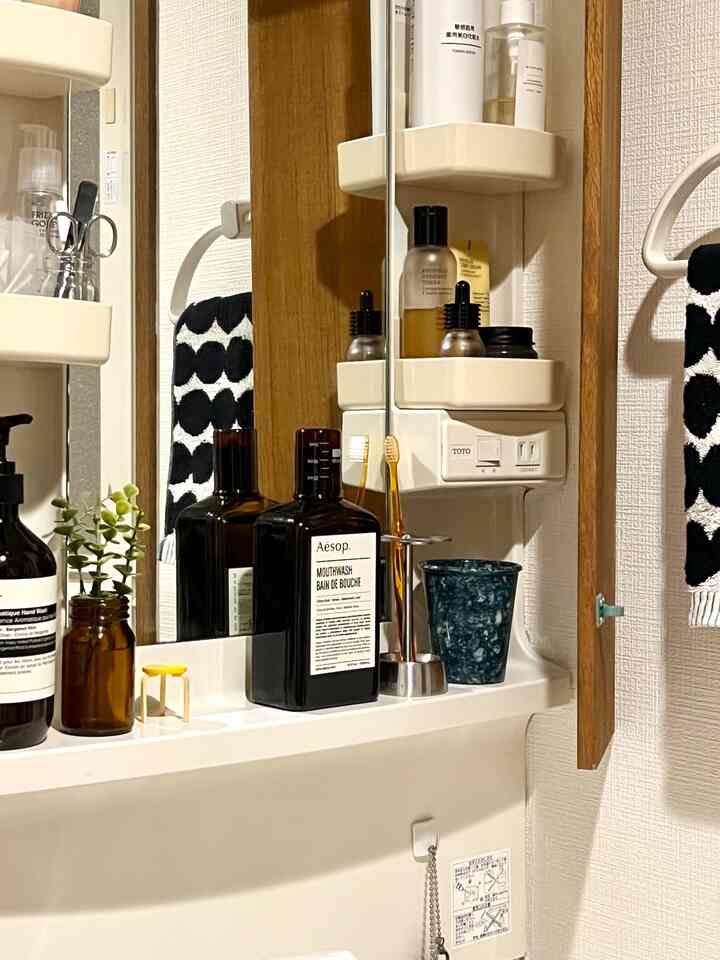 白と茶色のトーンのバスルーム棚にイソップのマウスウォッシュとタオルが整えられた清潔感のある空間