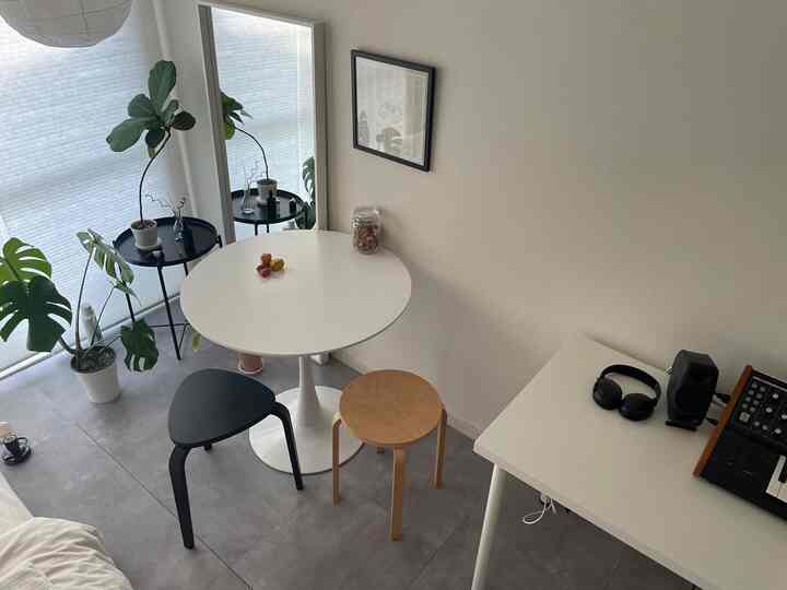 White and natural tone dining room featuring a round dining table with mismatched chairs in a simple, clean space