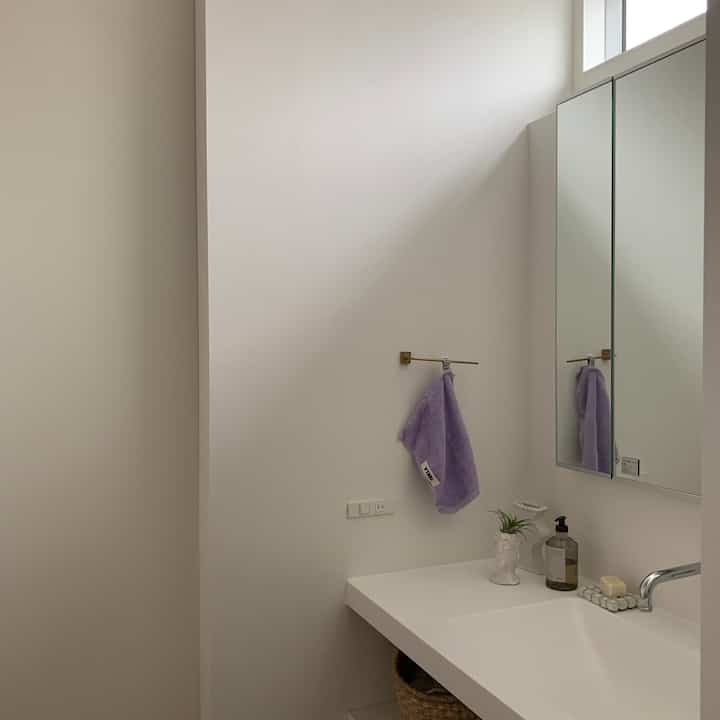 White and natural tone powder room featuring towel rack and vanity with a clean, minimalist atmosphere