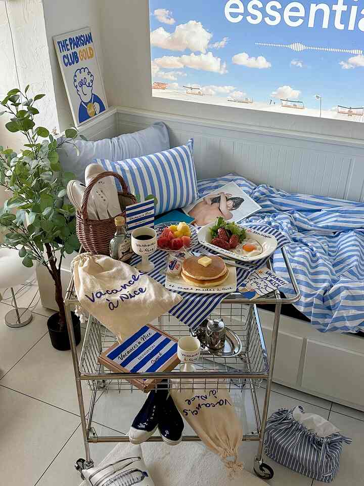 青と白のストライプの枕と寝具が配置された、朝食とおうちカフェの雰囲気が漂う明るく居心地の良いベランダ風の空間