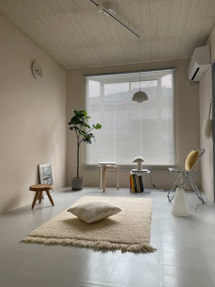 Beige and white toned bedroom featuring minimal furniture and blinds, creating a simple and cozy space