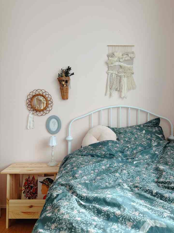 Kids' bedroom with beige walls and wooden stool, featuring floral bedding and wall decor creating a cozy atmosphere