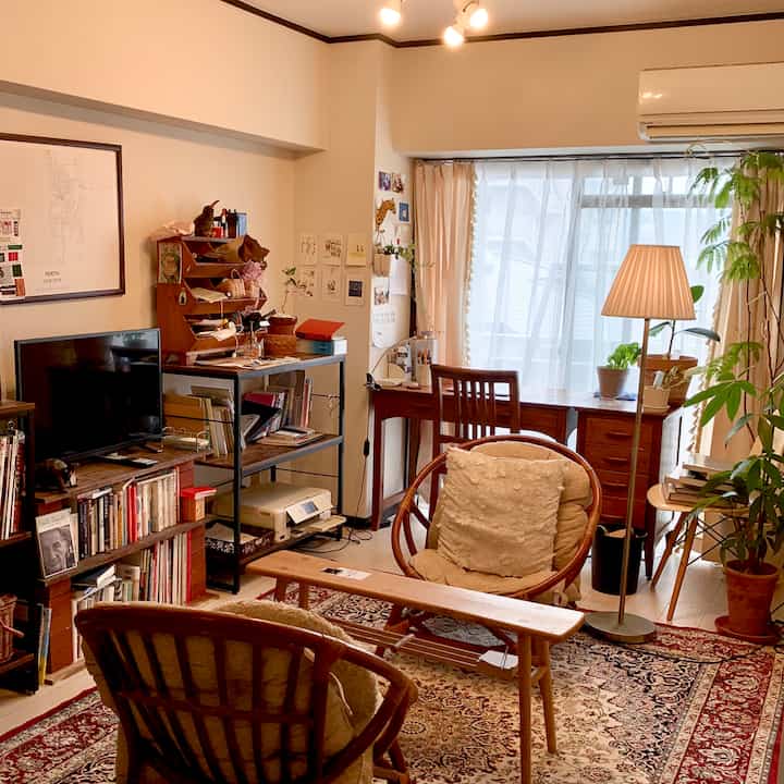 温かみのある木目調とベージュのリビング、ラグとフロアランプが置かれた雰囲気のあるおうちカフェ空間