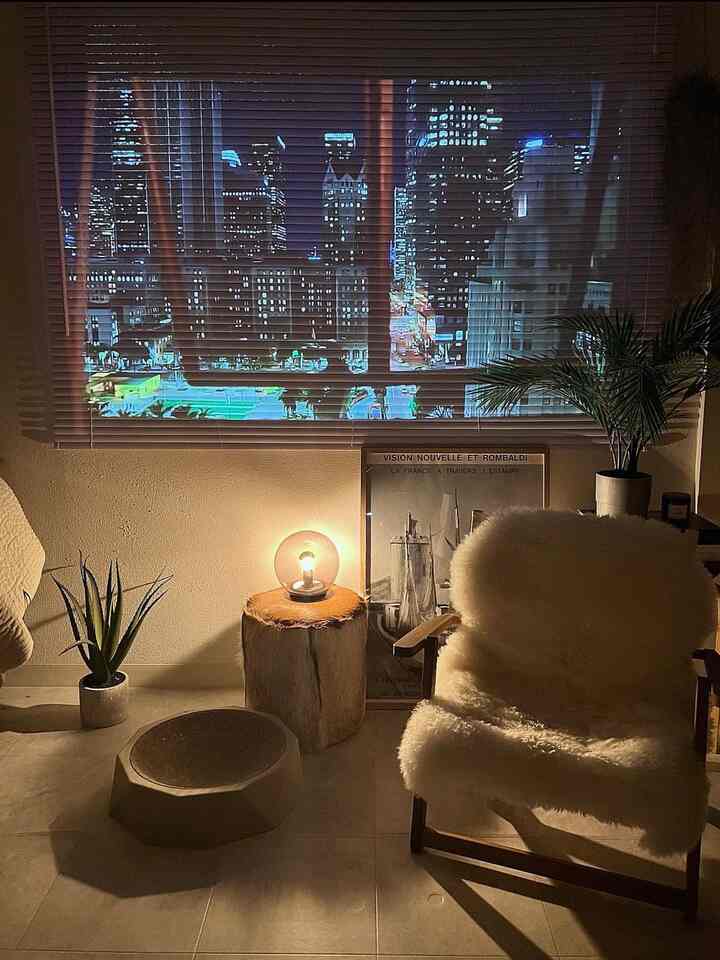 Beige-toned natural home cinema space featuring warm lighting, plants, and a cozy armchair