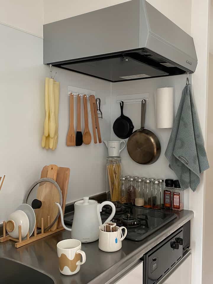 Gray and natural toned kitchen featuring hanging utensils and coffee equipment with a clean, organized atmosphere