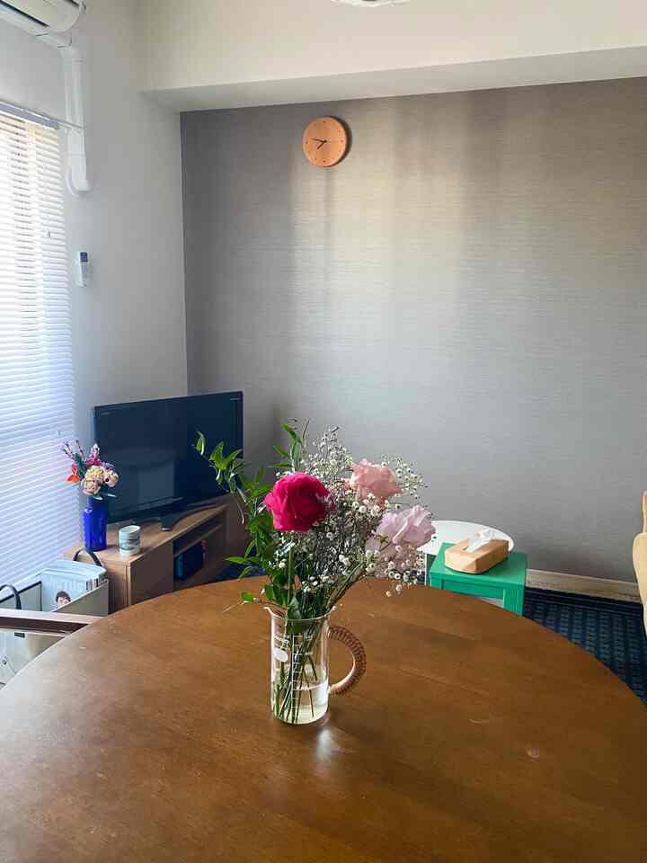 ナチュラルカラーのダイニングルーム、丸い木製のダイニングテーブルに生花の花瓶が置かれた、落ち着いた雰囲気のあるインテリア