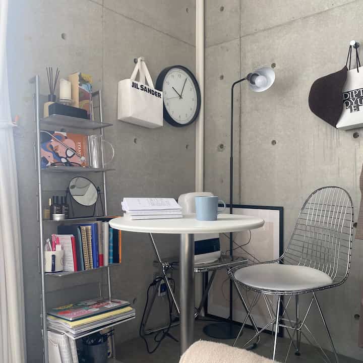 Light gray concrete walls with a white round table in a simple modern small home office space