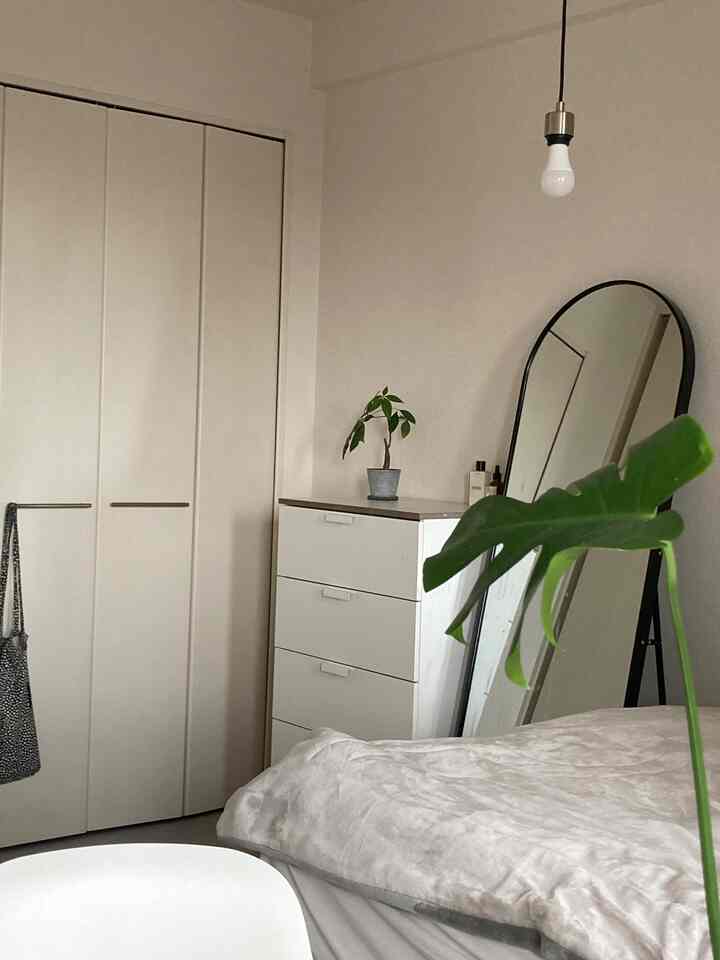 White-toned bedroom featuring a rounded arch mirror and dresser, with a clean and simple atmosphere