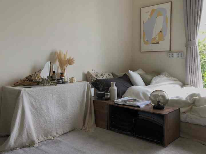 ナチュラルな色調の寝室、ベッドと木目調のナイトテーブル、ポスターが配置された落ち着いた雰囲気のインテリア