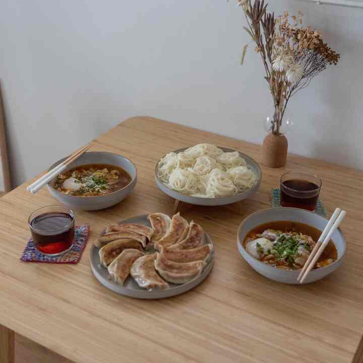 ライトブラウンの木目調が特徴のダイニング、グレーのセラミック食器と料理が配置された温かみのある雰囲気のインテリア