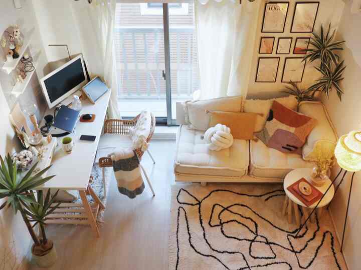 白とベージュのトーンのリビング、ソファ、デスク、ラグ、フロアランプが配置された雰囲気のある空間