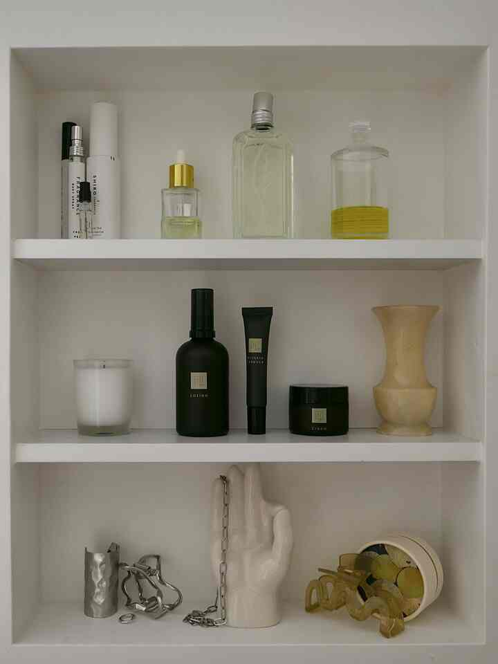 白を基調としたバスルームの棚、化粧品やキャンドル、オブジェが整然と配置された雰囲気のあるインテリア
