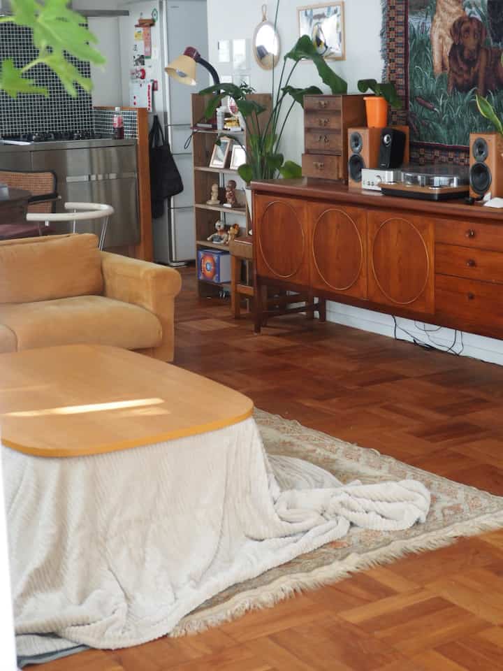 ナチュラルな木目調とベージュのソファがあるミッドセンチュリーモダンのリビング、温かく居心地の良い空間