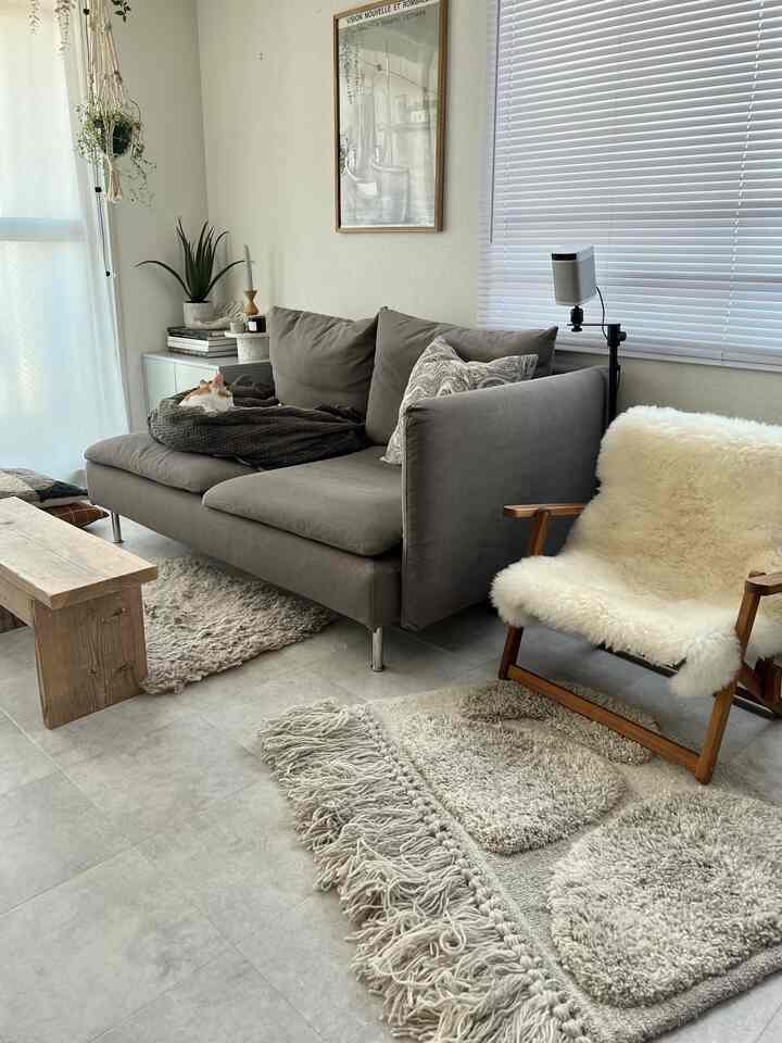 Light gray tiled floor living room featuring wood tone bench, gray sofa, and white blinds with a natural atmosphere