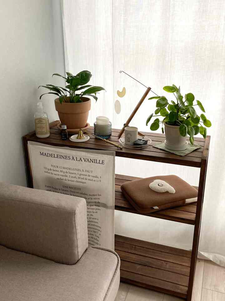 ナチュラルなブラウン色調のリビングのコーナー、窓際に置かれたオープンウッドラックと植物が調和する雰囲気のあるインテリア