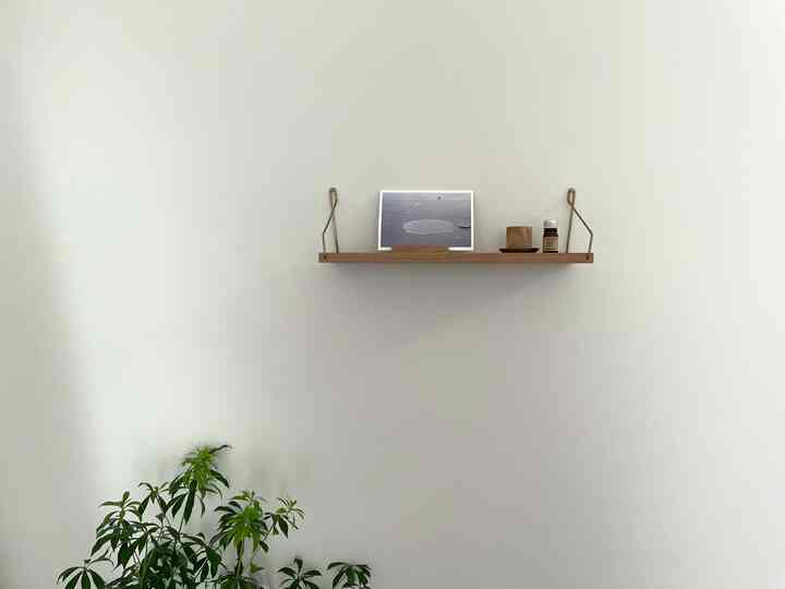 Minimal entrance space with white walls, a wood tone wall shelf featuring aroma items and green plant