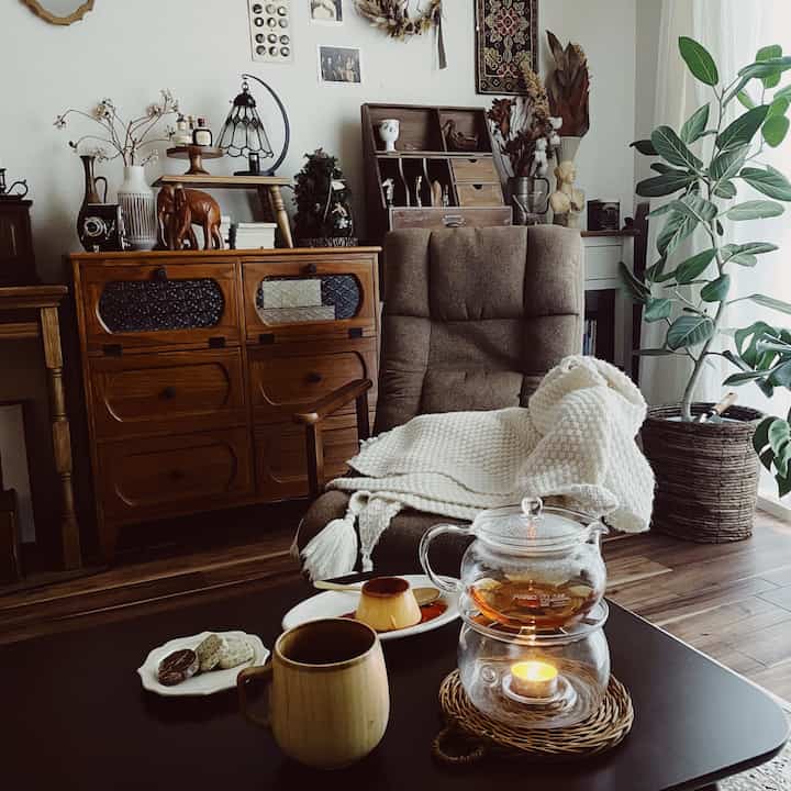 ブラウンとナチュラルな色調のリビング、アームチェアとチェストが配置され、ホームカフェの雰囲気がある印象的な空間