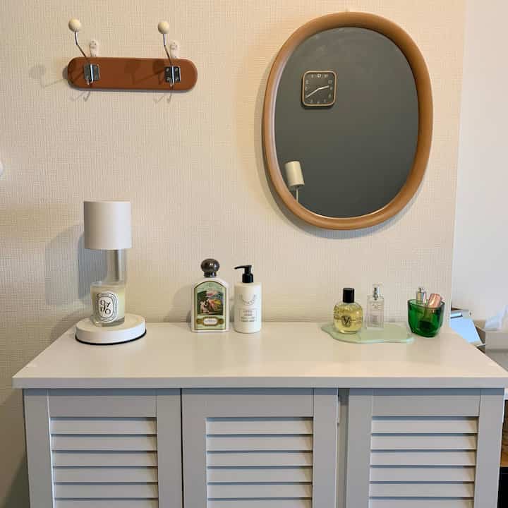 白い家具と木目調の鏡が配置されたリビング、清潔感とヴィンテージ感のある収納空間