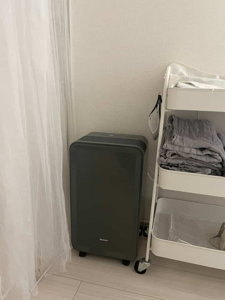 Simple and compact indoor space featuring a gray humidifier and white towel cart
