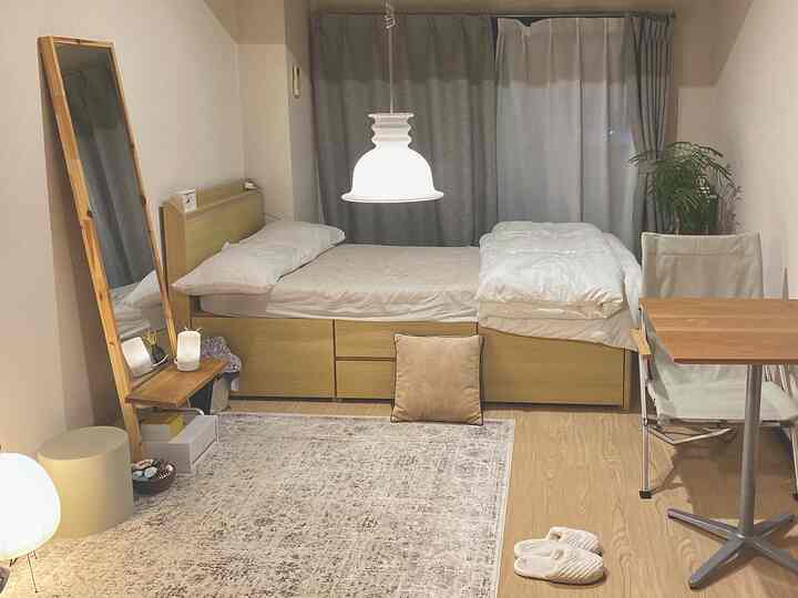 Compact bedroom with natural wood tones featuring a storage bed and workspace creating a simple atmosphere