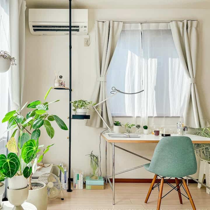 白とベージュのトーンのホームオフィス、複数の植物が配置され、自然で明るい雰囲気のあるインテリア