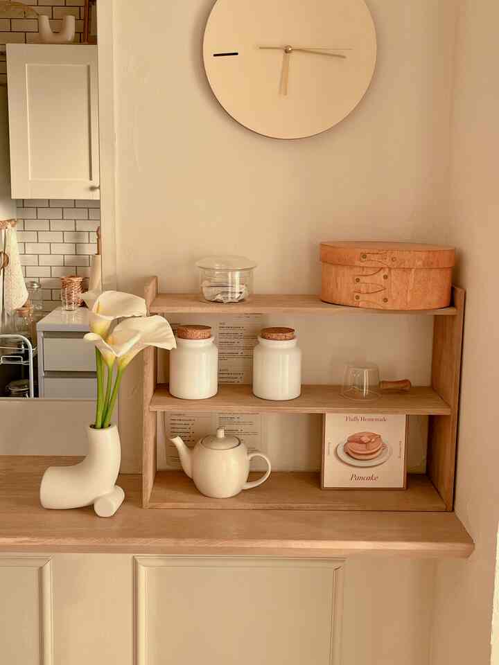 ベージュとナチュラルウッド調のキッチンダイニング、花瓶と額縁ポスターが配置された雰囲気のあるインテリア