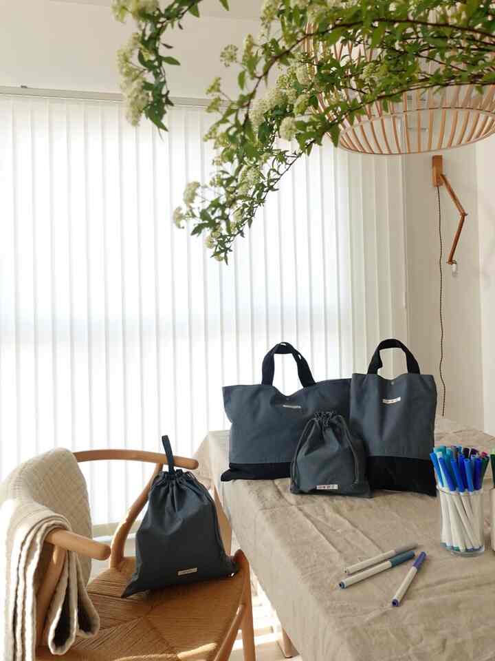 ベージュとナチュラルな色調のダイニングテーブルとチェアがあり、テーブルにはダークグレーのバッグが置かれた雰囲気のある空間