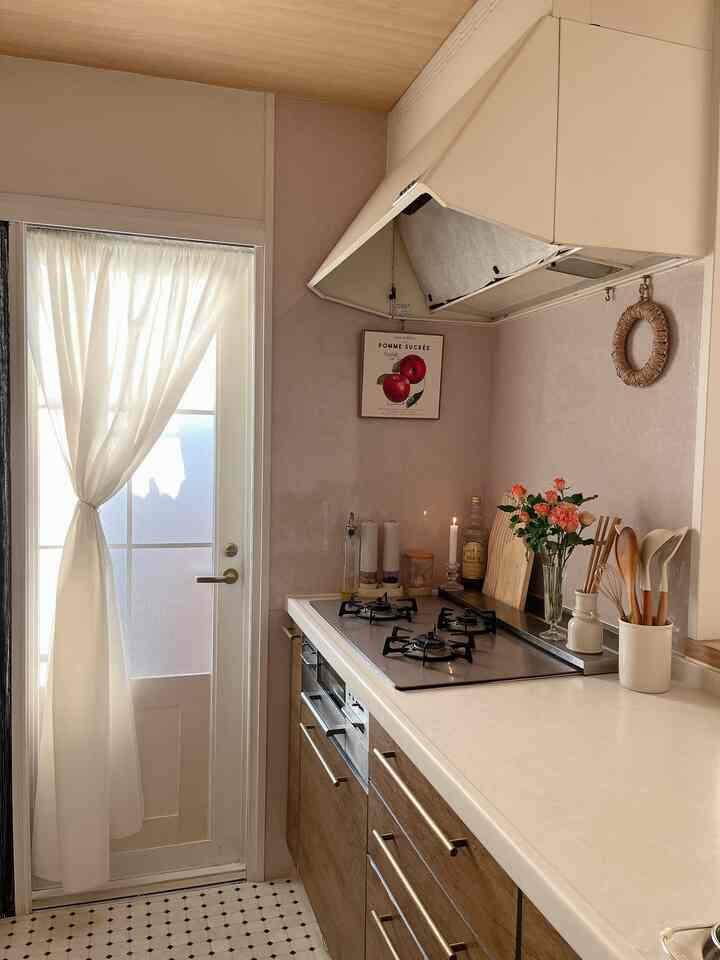 柔らかなベージュと木目調のキッチン、調理器具と花が配された雰囲気のある空間