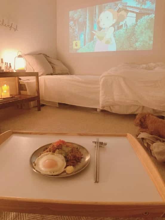 ベージュとナチュラルカラーの寝室兼リビング、木製トレイとキャンドルが配置された雰囲気のあるインテリア