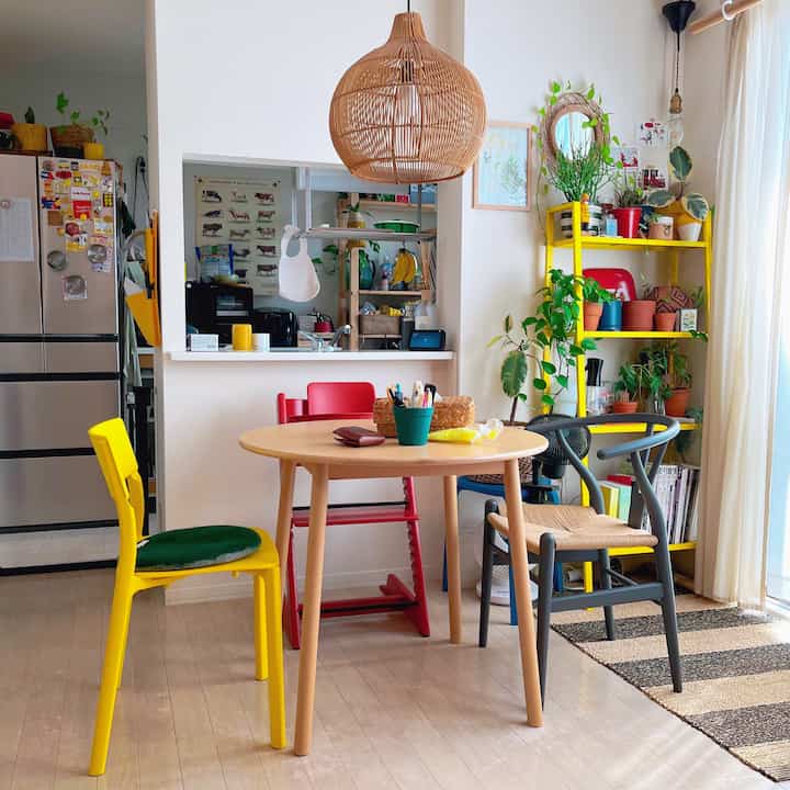 黄色とナチュラルウッドトーンが調和するダイニングルーム、豊富な植物が配置された明るく居心地の良い空間