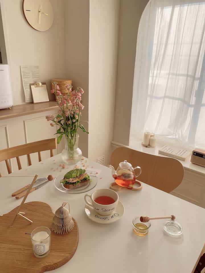 ベージュと木目調のキッチン、花瓶と紅茶、オープンサンドが配置された雰囲気のあるおうちカフェ空間