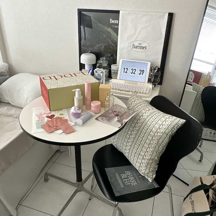 白と黒のトーンの小さな一人暮らしの部屋、テーブルとクッションが配置された雰囲気のあるインテリア