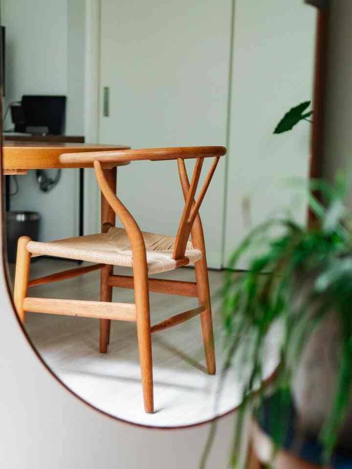 Natural toned dining room featuring a wooden Y Chair reflected in a mirror, creating a cozy and minimalist atmosphere
