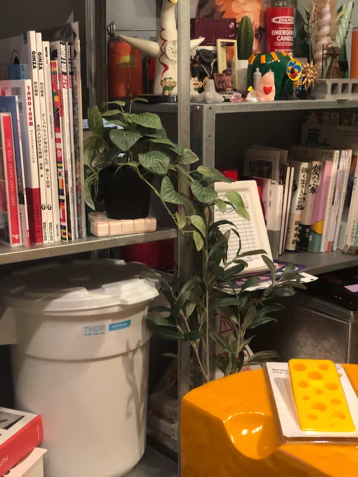 黄色のオブジェスツールと多様な装飾品、植物が置かれた金属棚の隙間収納スペース