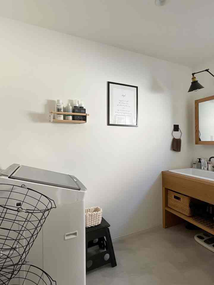 白とナチュラルウッド調のホテルライクでシンプルな縦長ワンルーム型のランドリールーム、収納バスケットとアイアン小物が配置された雰囲気のあるインテリア