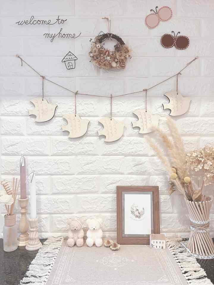 ナチュラルカラーの玄関、木製の鳥のガーランドやドライフラワー、キャンドルスタンドが配置された雰囲気のあるインテリア