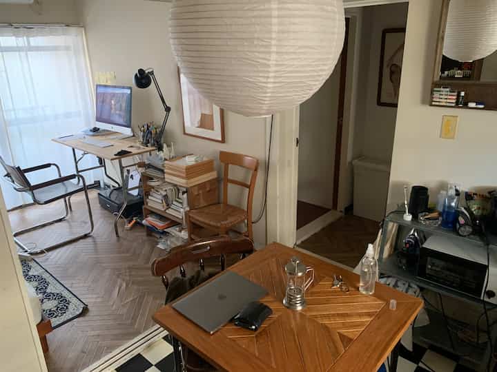 ナチュラルな木目調とモダン家具が調和した、小さなアパートのリビングにあるホームオフィススペース