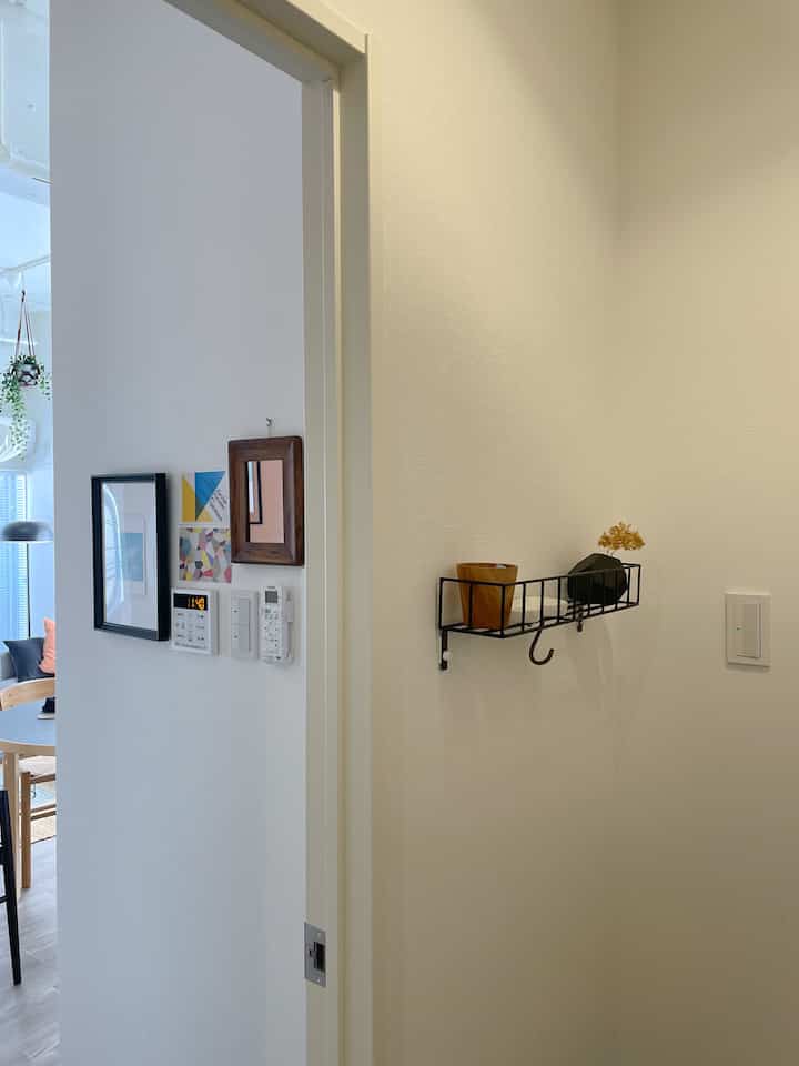 White-toned entrance wall featuring black picture frames and a small storage shelf, creating a simple modern space