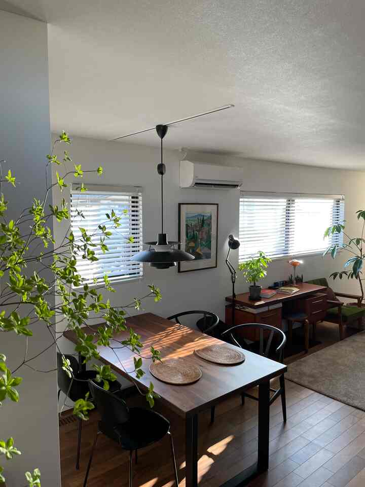 白い壁と茶色の家具が調和するナチュラルモダンなリビングとダイニング空間、緑色の植物が雰囲気を彩る印象的なインテリア