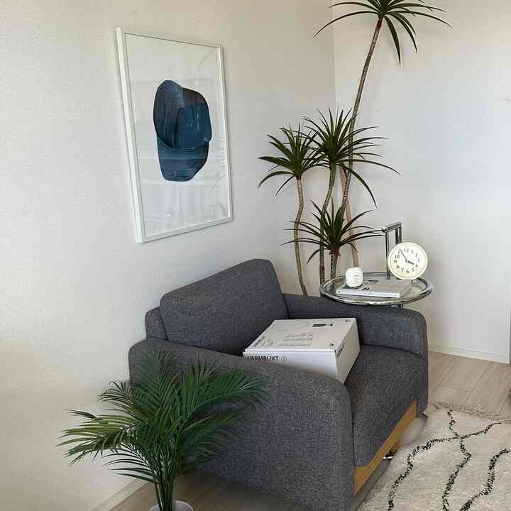 白い壁とグレーの一人掛けソファが置かれた、シンプルでゆったりとしたリビング空間