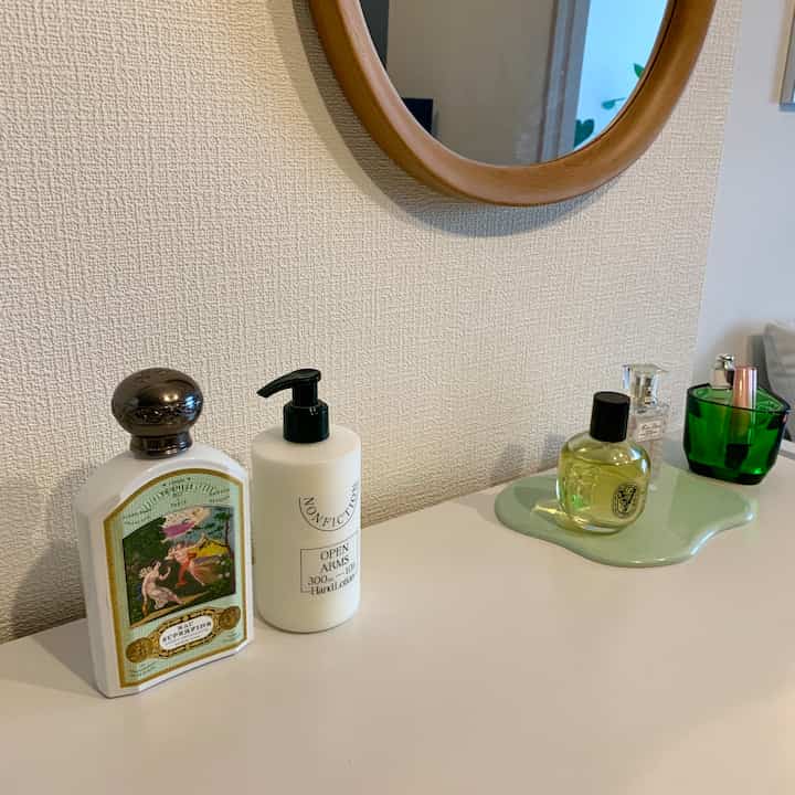 Natural color living space with wooden round mirror and cosmetics on a tray on clean dresser surface