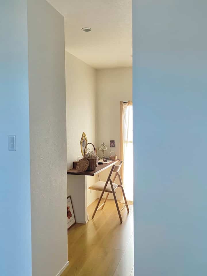 Natural-toned space featuring a walk-in closet entrance with bright white walls and light brown wooden flooring under soft natural light