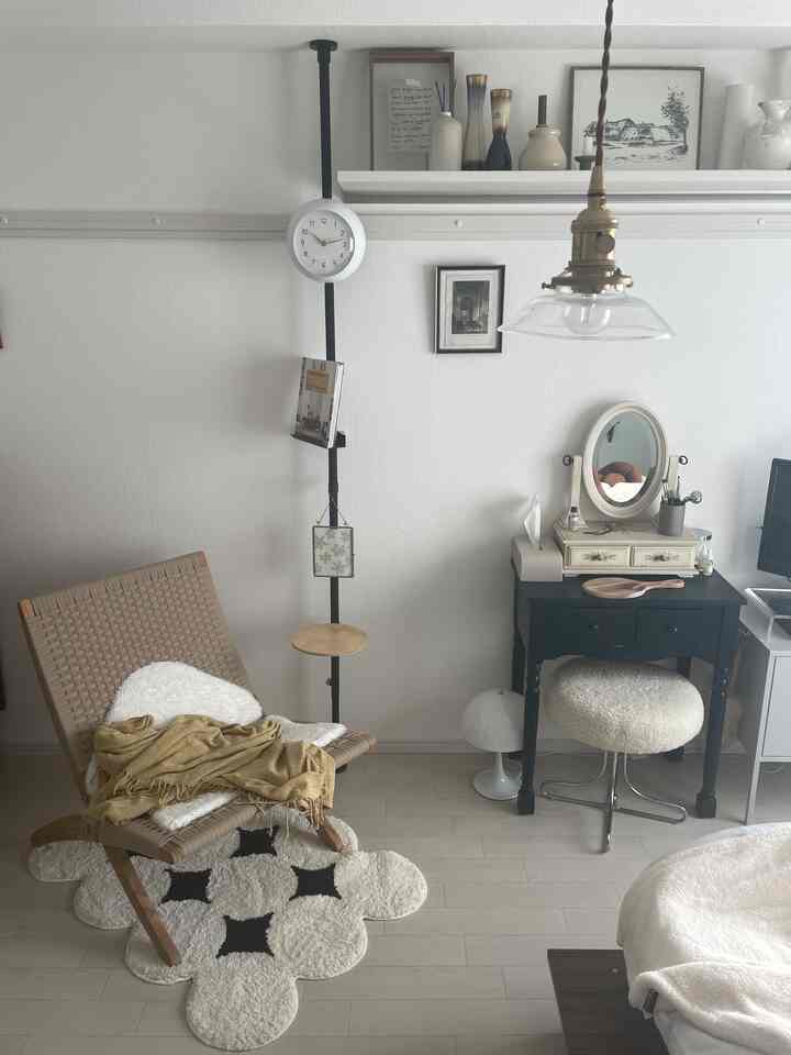 ナチュラルカラーの寝室、ヴィンテージの化粧台と編み込みアームチェア、ペンダントライトが配置された雰囲気のあるリラックス空間